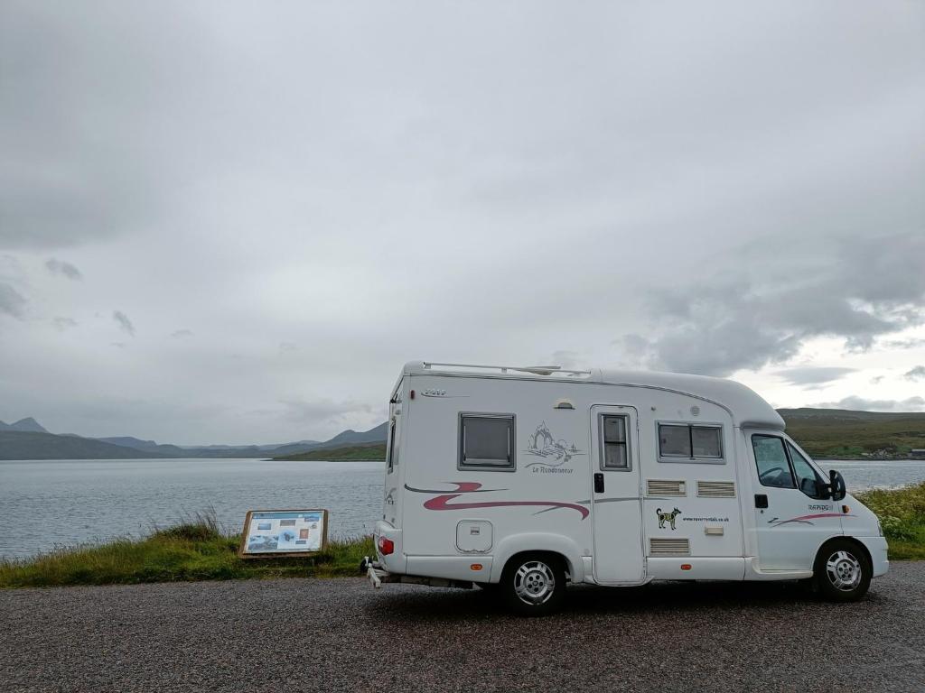 a white caravan parked on the side of a lake at Rover Rentals in Inverness