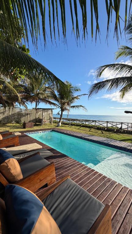 a swimming pool with chaise lounge chairs next to the ocean at Vila Sereia Caraiva in Caraíva