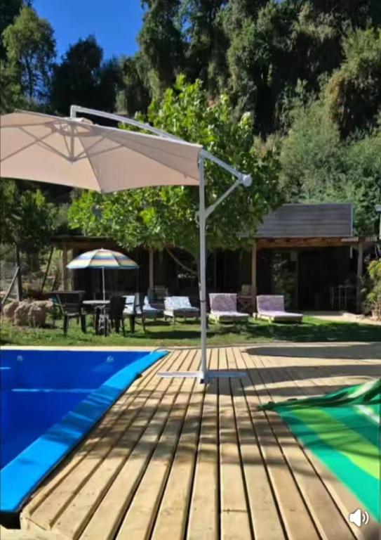 a patio with an umbrella next to a swimming pool at Radal Riverside Lodge in El Torreón