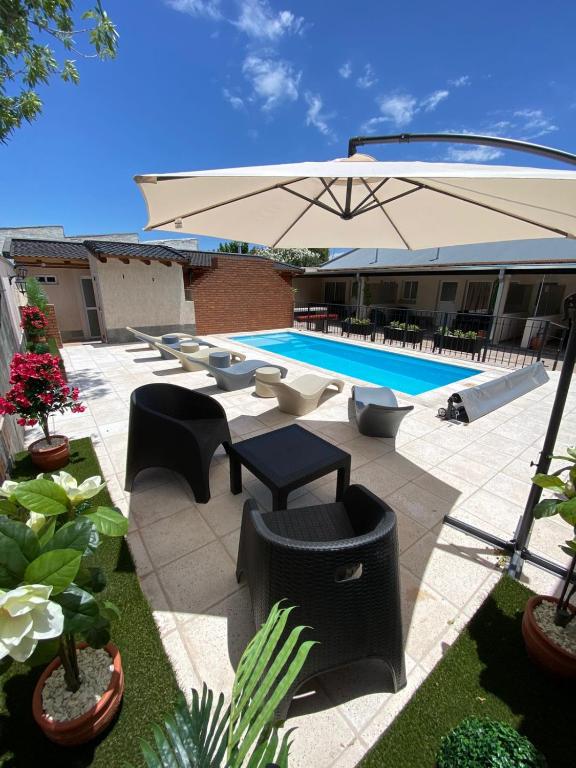 a patio with an umbrella and chairs and a pool at Etel Departamentos in San Rafael