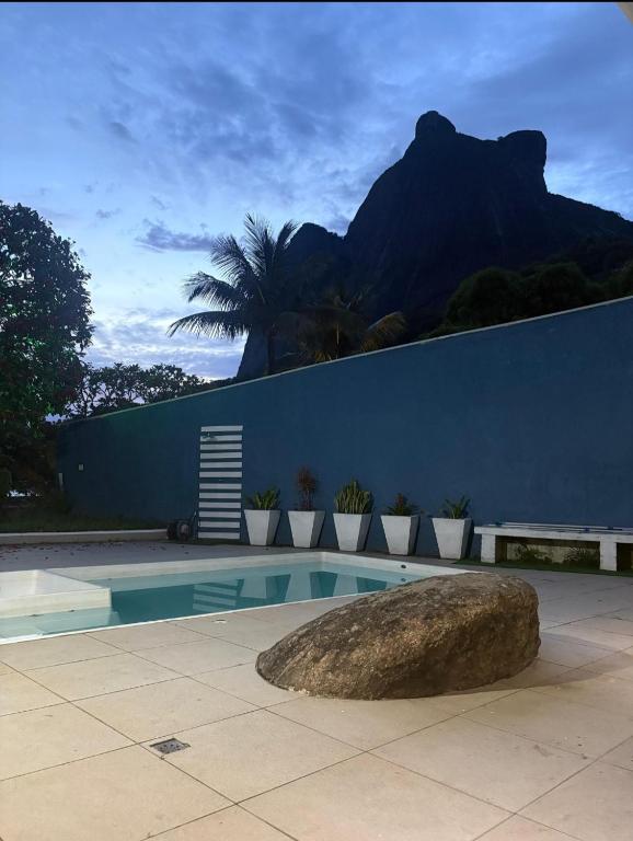 a swimming pool with a rock in front of a wall at Casa Caminho do Meio in Rio de Janeiro