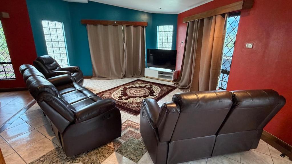 a living room with two leather chairs and a television at Blissfull Corner at Centerpoint Unit 1 in Suva