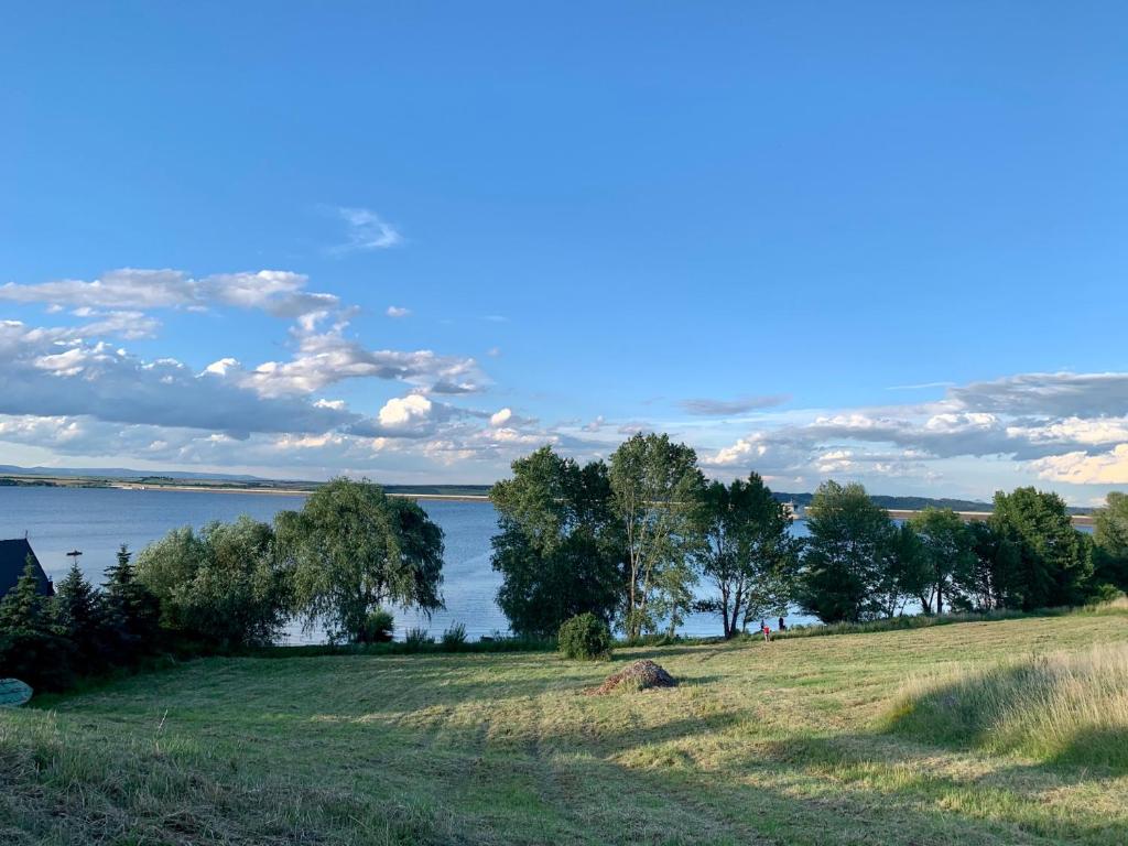 a grassy field with a view of a body of water at Rybářská bašta-Vikletice in Kwon
