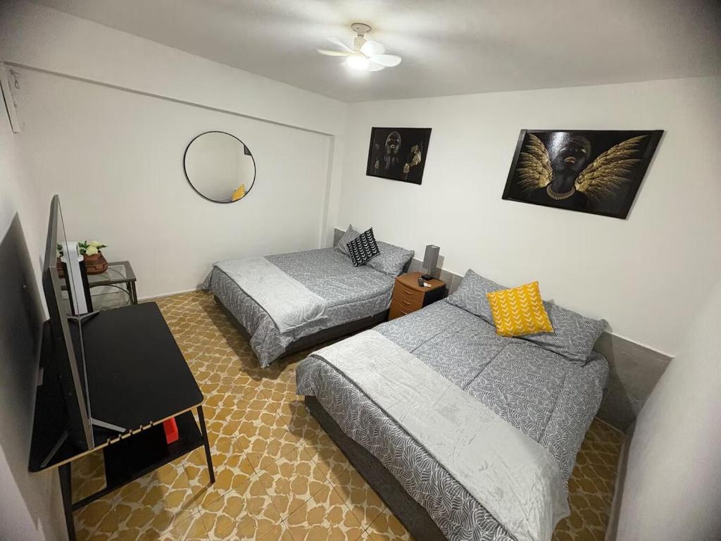 a bedroom with two beds and a tv and a mirror at Departamento céntrico y cómodo La Casona in Xalapa