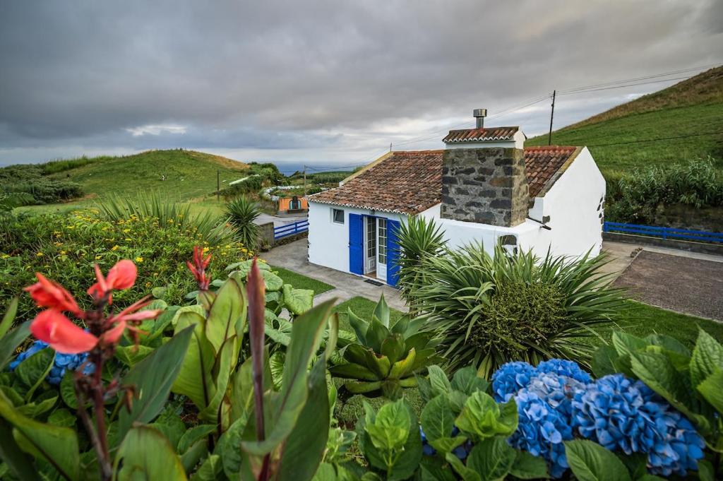 a small white house with blue doors in a garden at Villa Pico de Mafra in Mosteiros