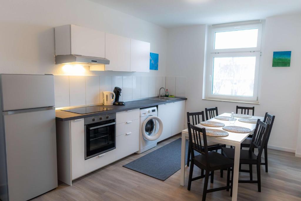 una cucina con un tavolo e un frigorifero bianco di Kaiserbrunnen Gastromeile, City, Messe & Stadionnah a Dortmund