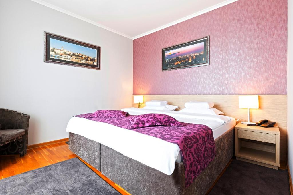 a hotel room with a large bed with purple sheets at Garni Hotel Nevski in Belgrade