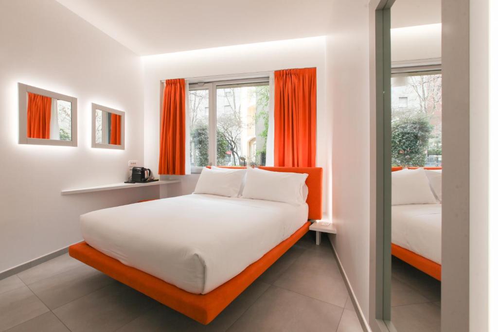 ein Schlafzimmer mit zwei Betten und orangefarbenen Vorhängen in der Unterkunft The Grove in Mailand