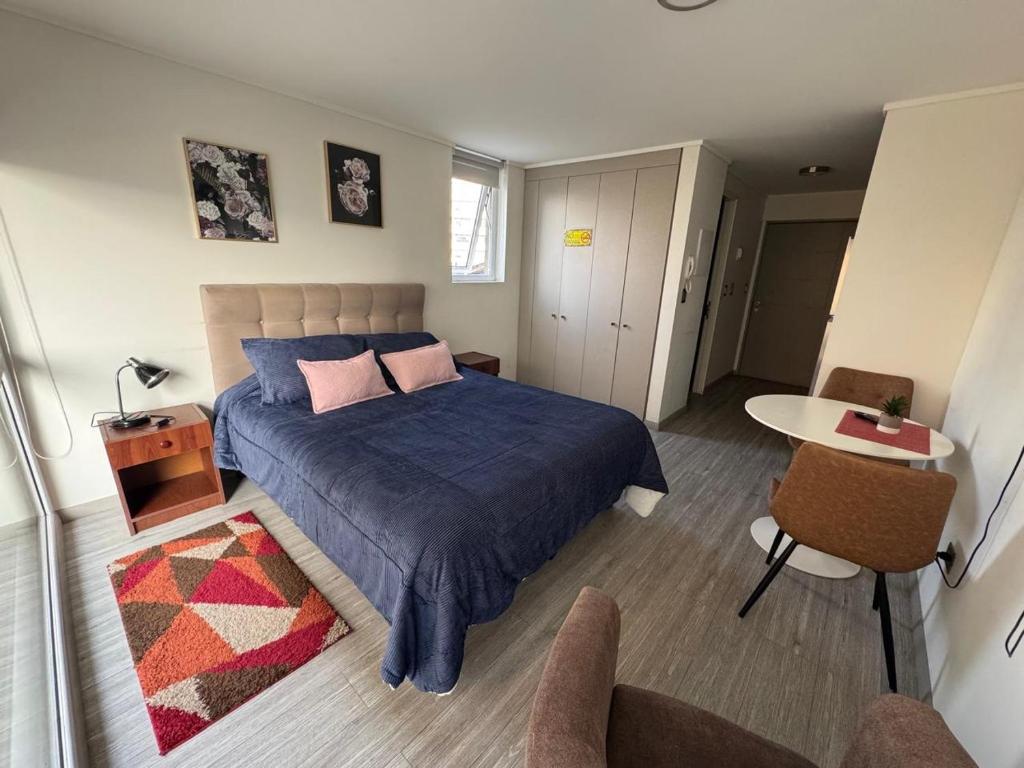 a bedroom with a blue bed and a table and chairs at Departamento studio. in Temuco