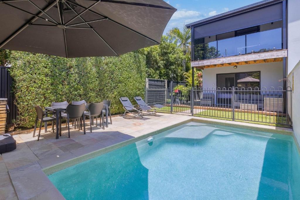 a swimming pool with a table and an umbrella at Palmy Villa in Gold Coast