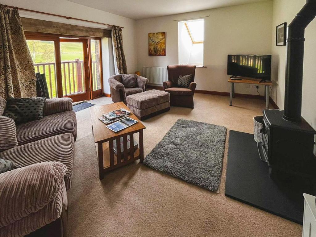 a living room with a couch and a stove at Quarry Cottage in Penrith