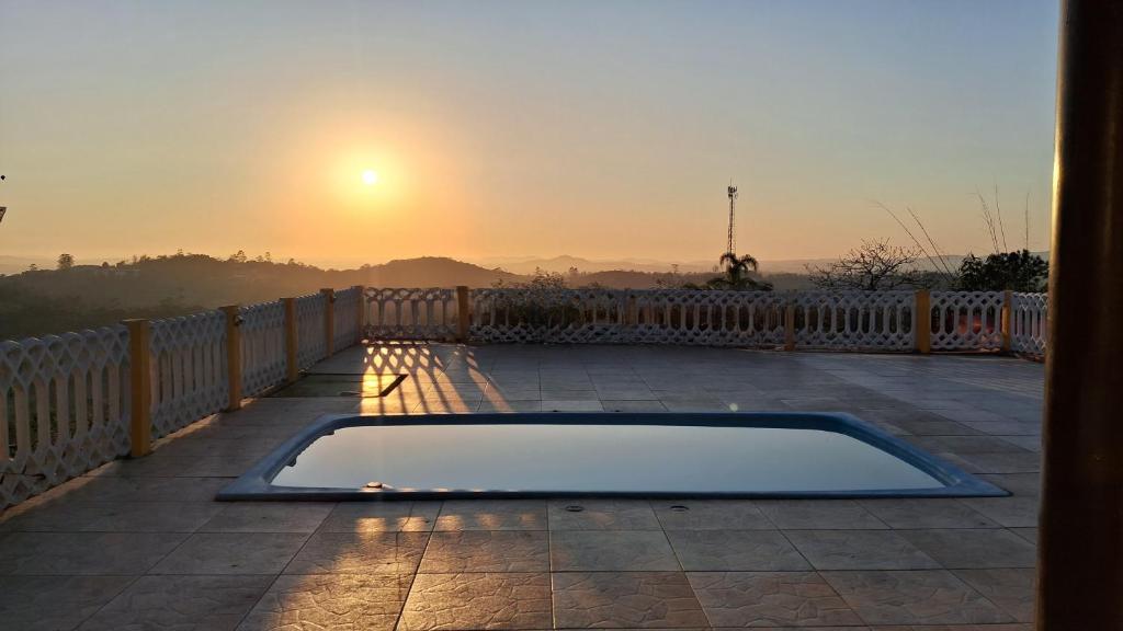 a pool on a balcony with the sunset in the background at Chácara Pagliai e Bueno in Suzano