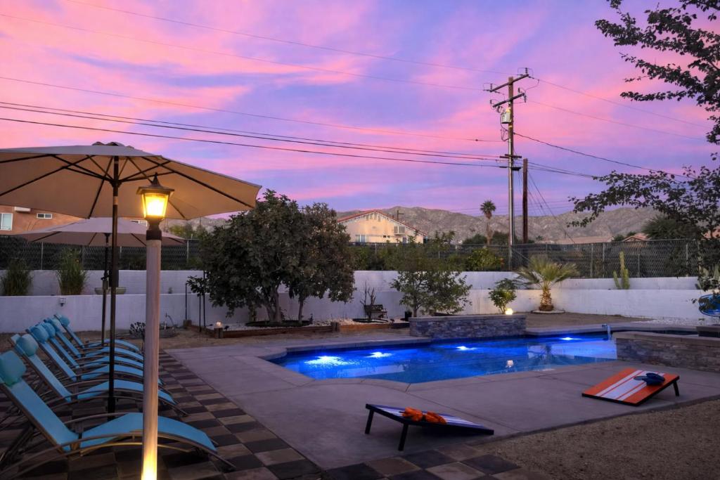 a swimming pool with two chairs and an umbrella at Casa Pueblo in Desert Hot Springs