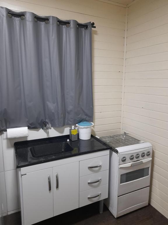 a kitchen with a sink and a stove at Casa Contêiner Azul in Rosário do Sul