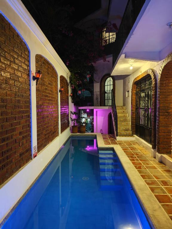 an indoor swimming pool with a brick wall and purple lighting at Casa Rey Sol Vallarta in Puerto Vallarta