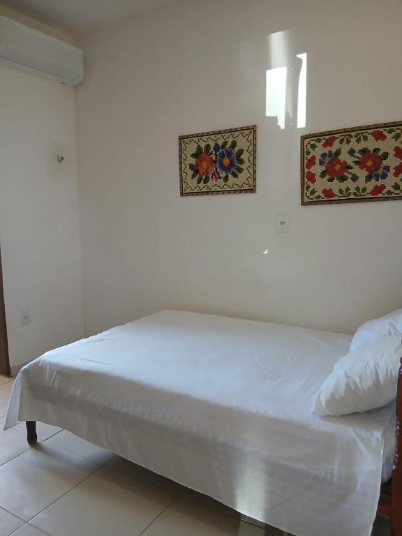 ein Bett in einem Zimmer mit zwei Bildern an der Wand in der Unterkunft NuHostel in Conde