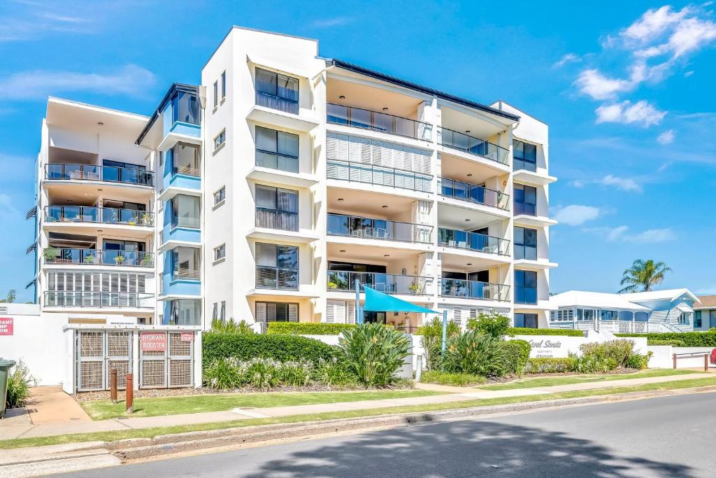 a white apartment building with blue balconies on a street at Coral Sands 503 in Bargara