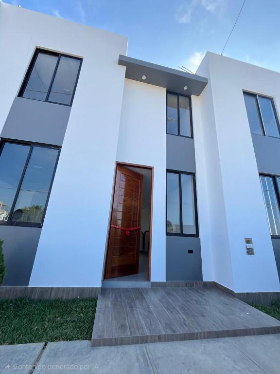 a white house with a red door at Pimentel Casa in Chiclayo