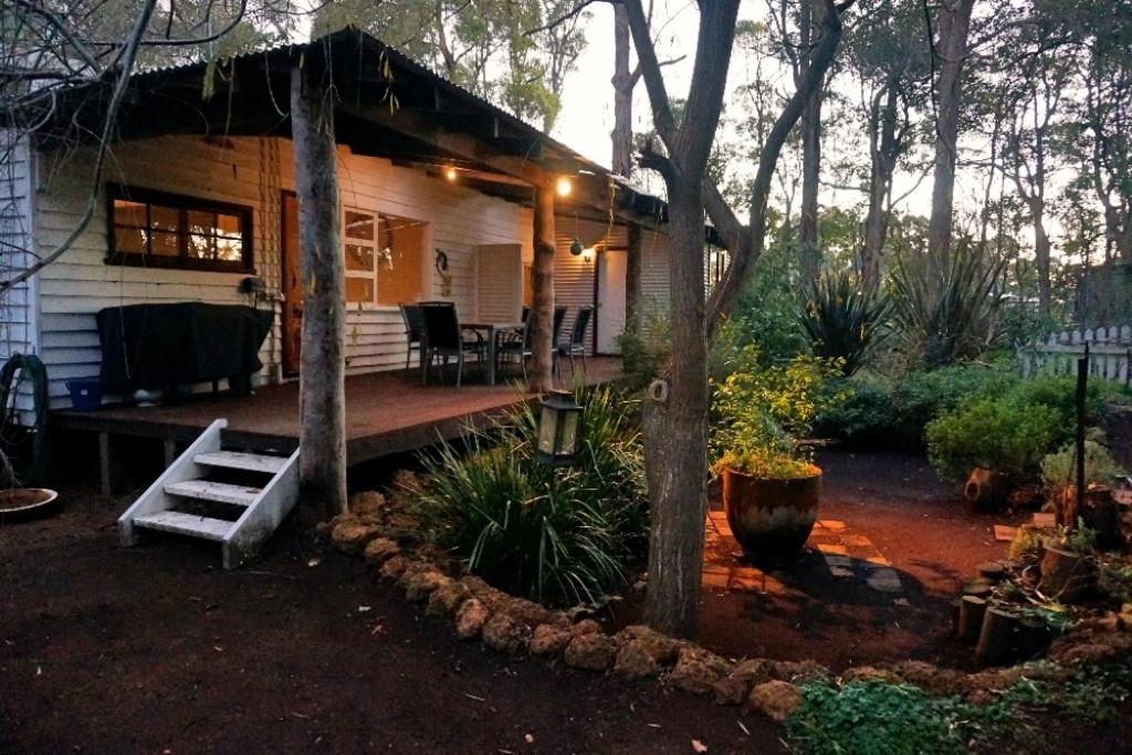 a house with a porch with a bench in the yard at Banana Pancakes in Margaret River Town