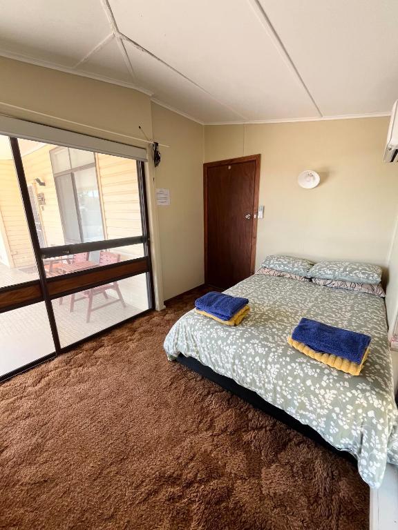 a bedroom with a bed with two blue pillows on it at Stay @ Ray's in West Wyalong