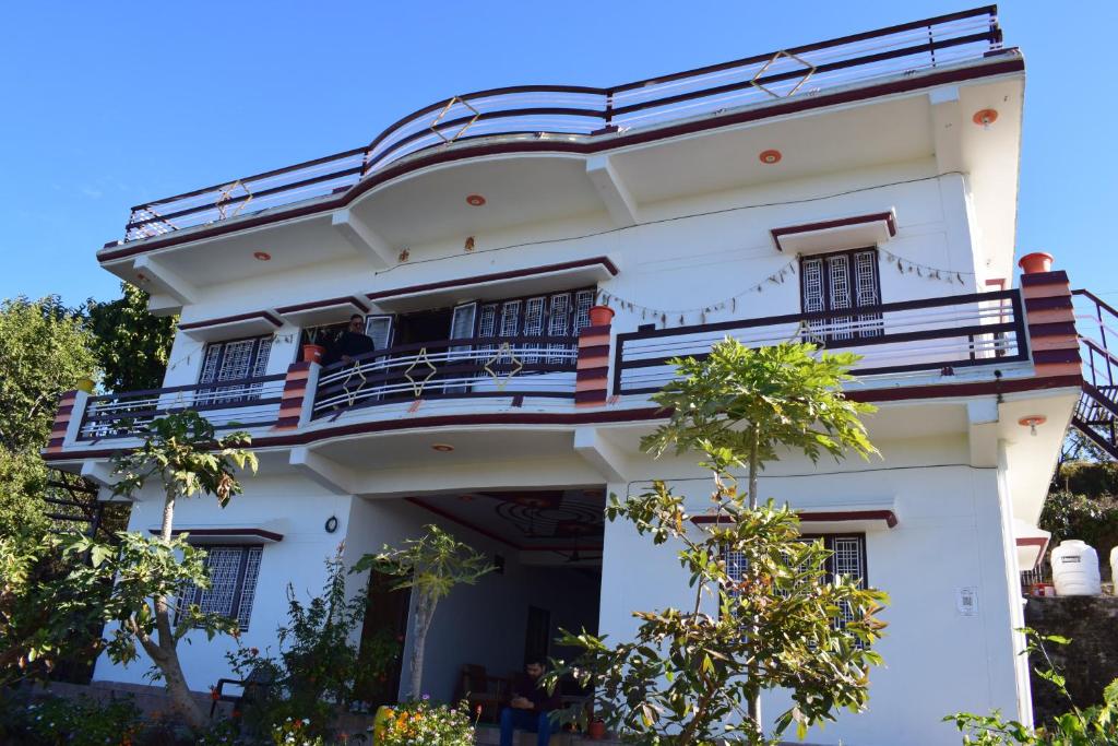 a white building with a balcony on it at Rameshwari Homestay in Lansdowne