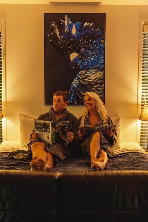 a man and a woman sitting on a bed at Amore On Buderim Rainforest Cabins in Buderim