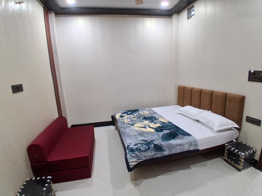 a bedroom with a bed and a red chair at JSRInn in Mathura
