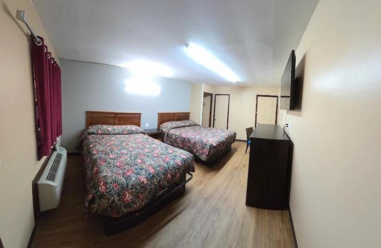 a hotel room with two beds and a television at Candle Light Motel in Ozark