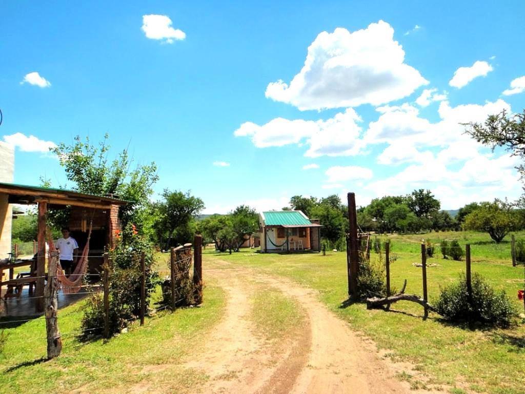 un camino de tierra en frente de un campo con una casa en Pasos Cortos Cabañas Nono en Nono