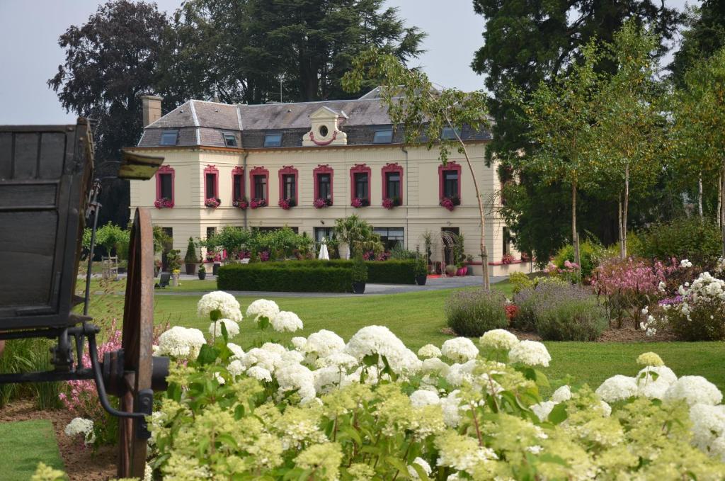 una grande casa bianca con finestre rosse e fiori di Le Domaine des Fagnes a Sains-du-Nord