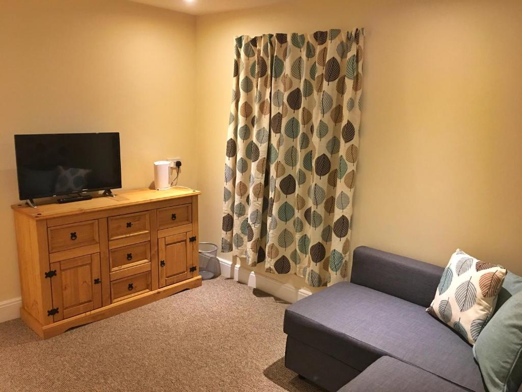 a living room with a couch and a flat screen tv at Camelot Seafront Hotel in Blackpool