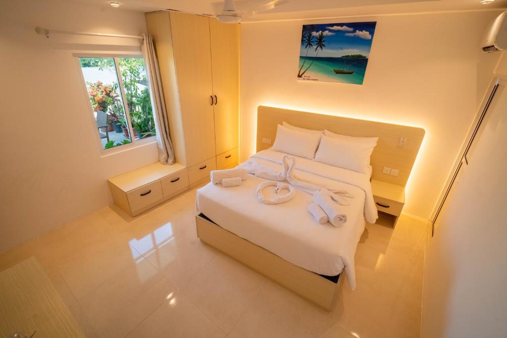 a bedroom with a bed with two towels on it at Vilu Himmafushi in Himmafushi