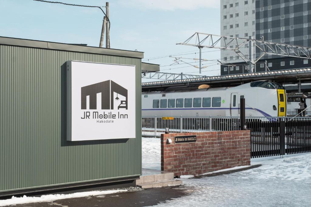 a sign in front of a building with a train at JR Mobile Inn Hakodate in Hakodate