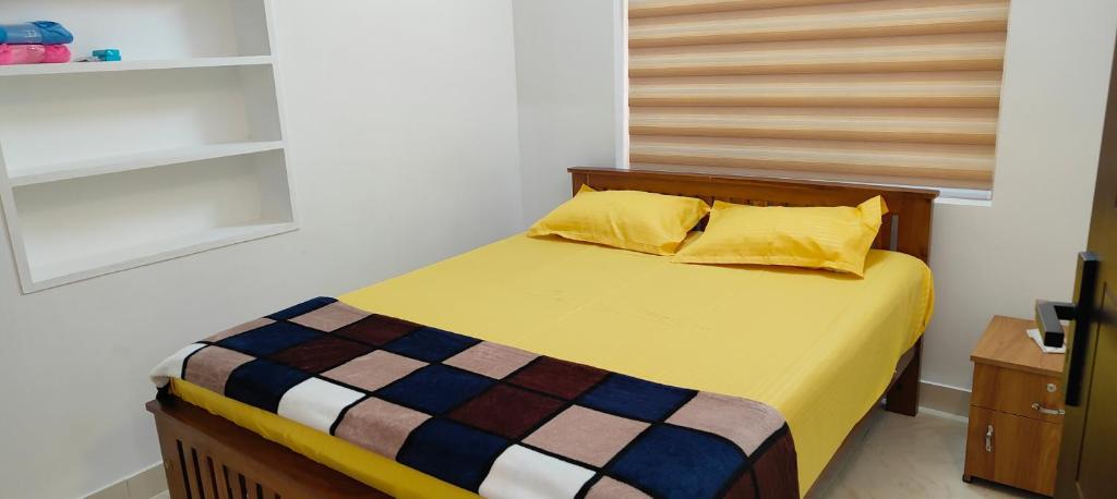 a bedroom with a bed with two yellow pillows at Ivory Suites Meadows in Kozhikode