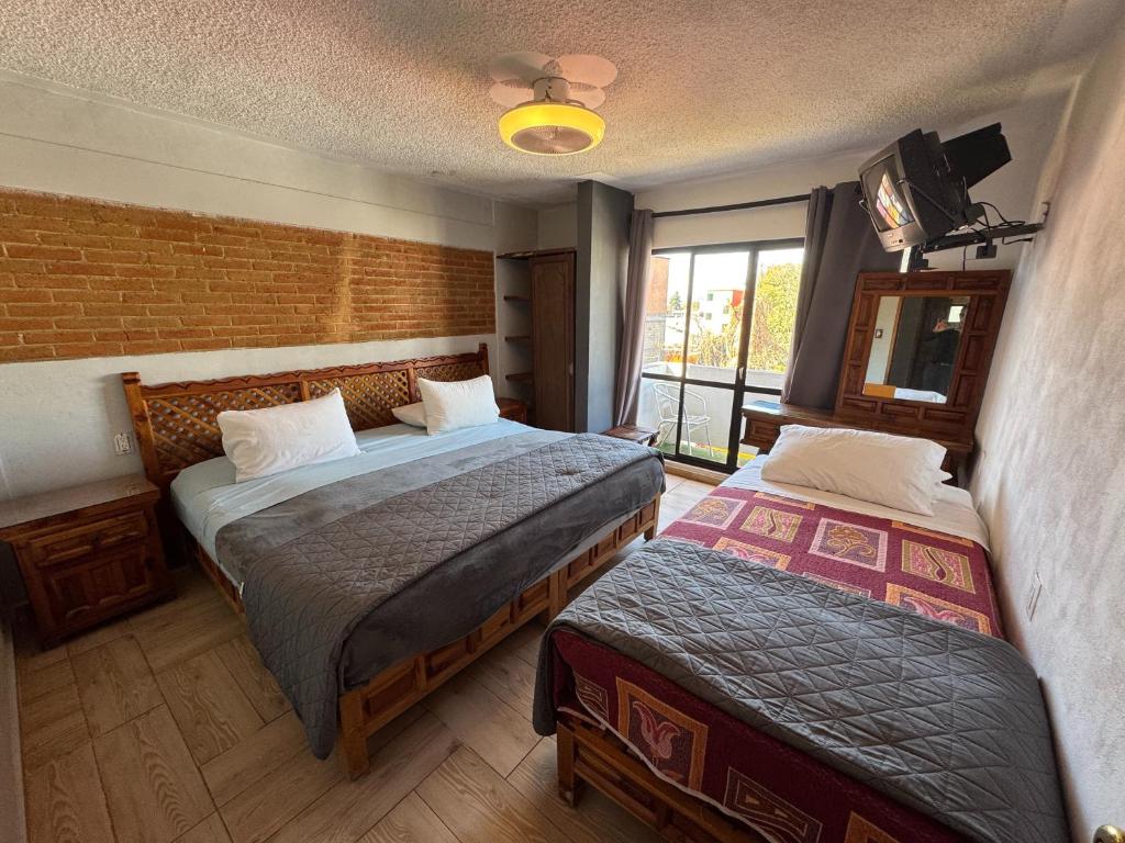 a hotel room with two beds and a window at Hotel Bungalows La Era in Ixtapan de la Sal