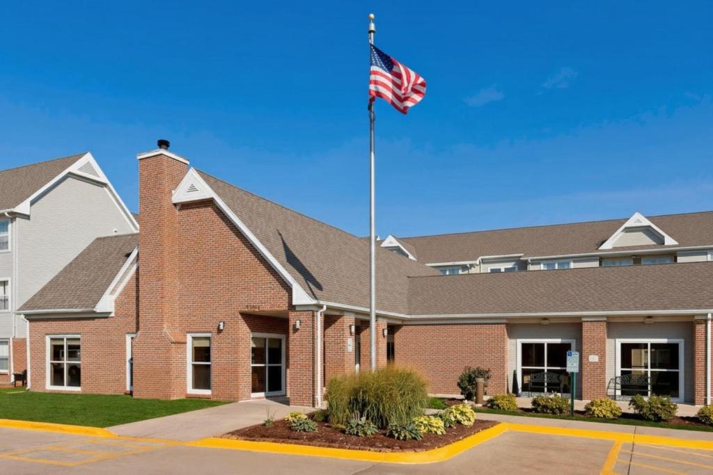 an american flag flying in front of a brick building at PrimeStay Extended Suites by IHG in Madison