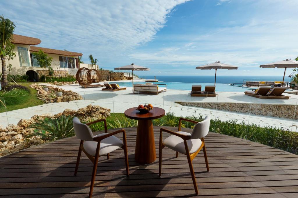 a patio with a table and chairs and the ocean at Vanara Resort and Spa in Uluwatu