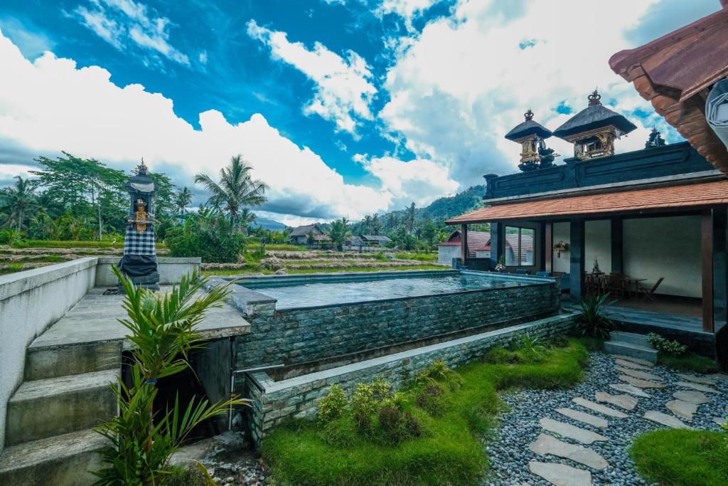 a villa with a swimming pool in front of a house at Arsyana Villa in Sidemen