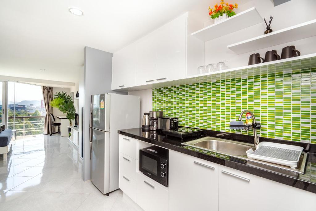 a kitchen with a sink and a green tile wall at Hua Hin Condo C - Maysa & Hin Nam in Hua Hin