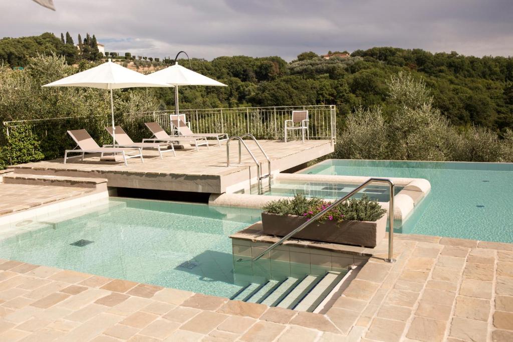 a swimming pool with chairs and an umbrella at Agriturismo La Romagnana in Pistoia