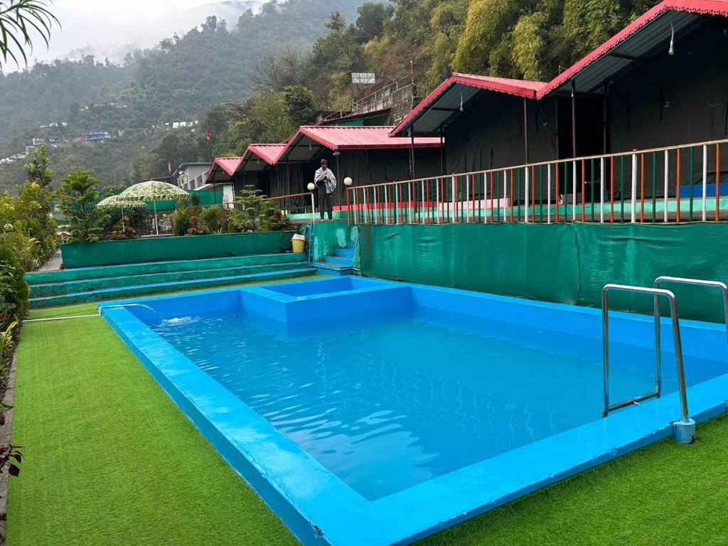a large blue swimming pool next to a house at Shivpuri Hills Camp in Jāmb