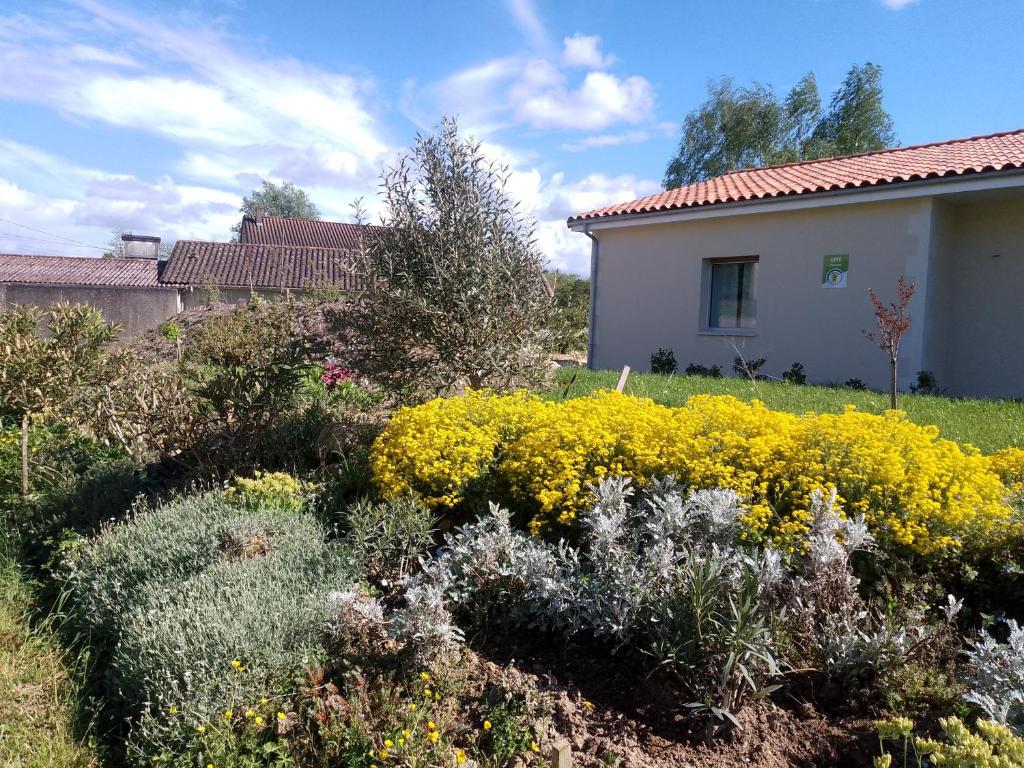 a garden with yellow flowers in front of a house at domaine de marodi jasmin in Baignes-Sainte-Radegonde