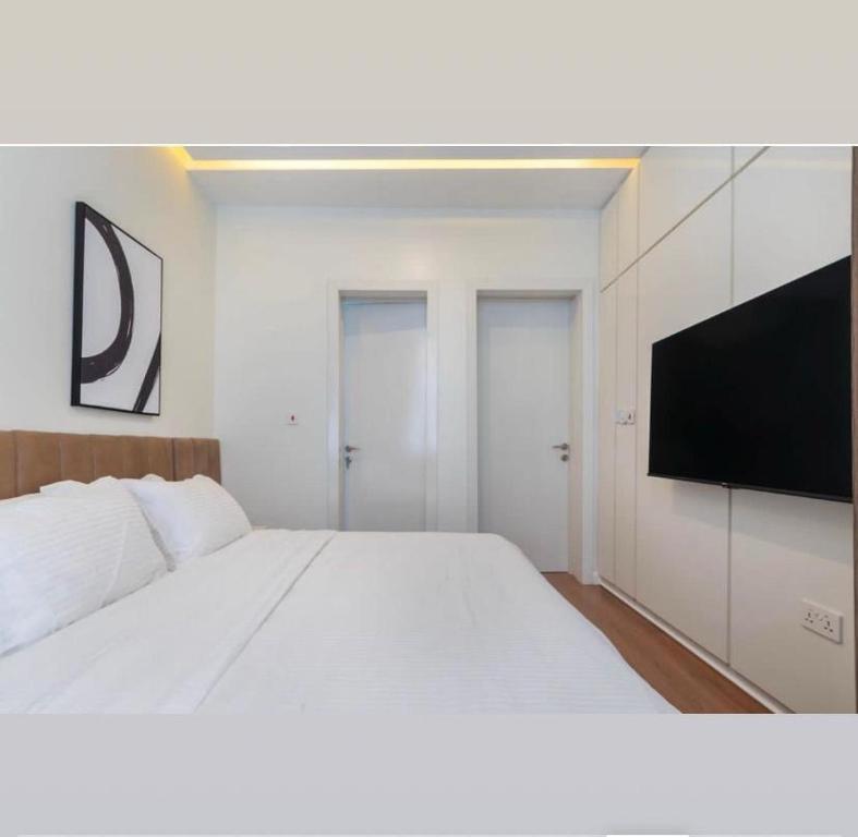 a bedroom with a white bed and a flat screen tv at Home helpers in Lagos