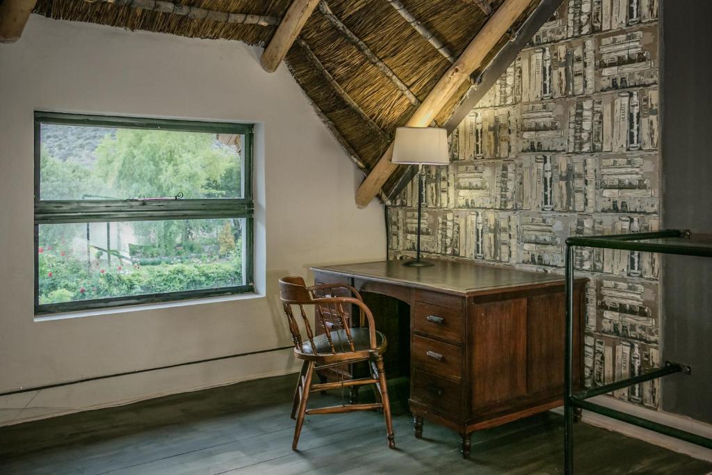 a desk and a chair in a room with a window at The Whyte House in Graaff-Reinet
