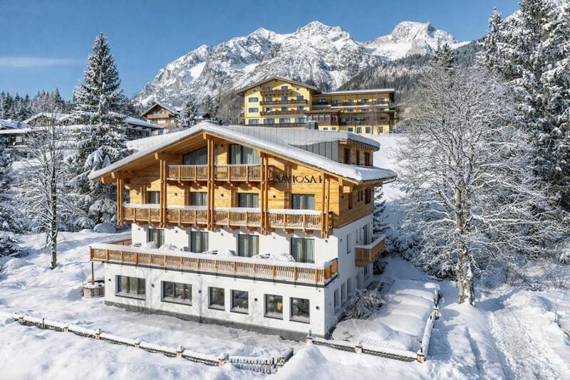 a house in the snow with mountains in the background at Pension Savisalo in Ramsau am Dachstein