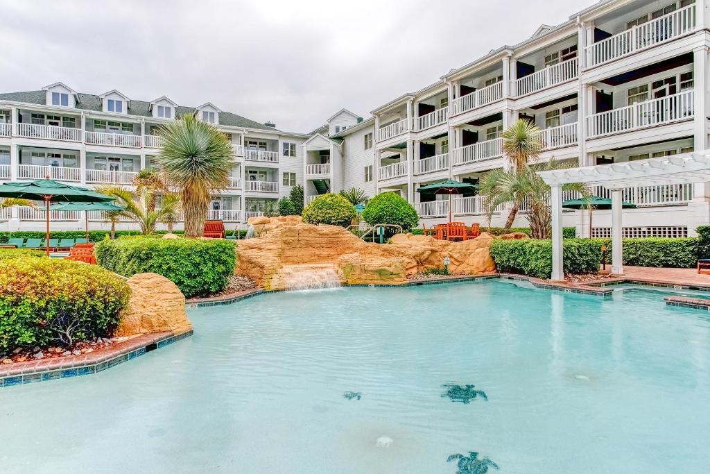 a swimming pool in front of a large apartment building at Turtle Cay Resort in Virginia Beach