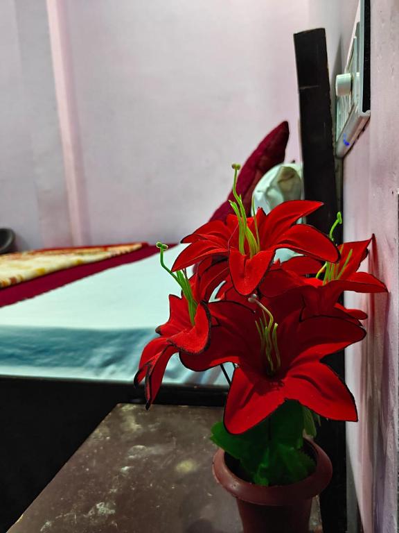 a red flower in a vase next to a bed at Shri Prabhu guest house in Ayodhya