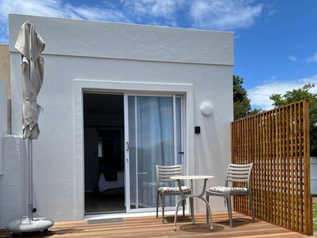 a white house with chairs and a table on a deck at Mountain View Studio Hermanus in Hermanus
