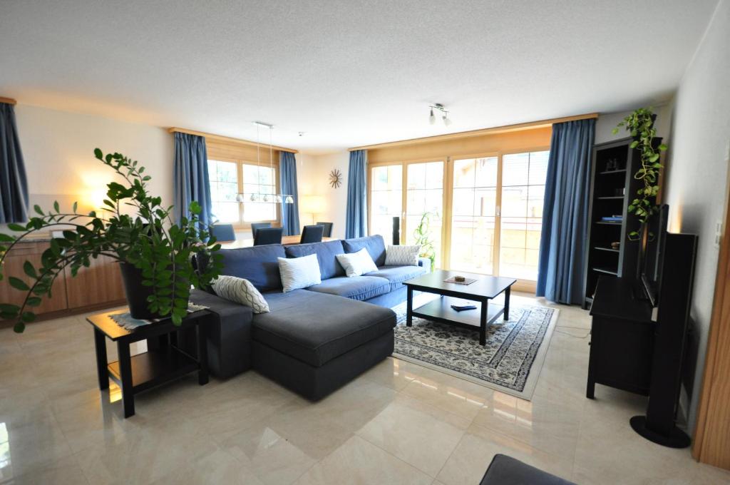 ein Wohnzimmer mit einem blauen Sofa und einem Tisch in der Unterkunft Family Frame Apartment in Lauterbrunnen