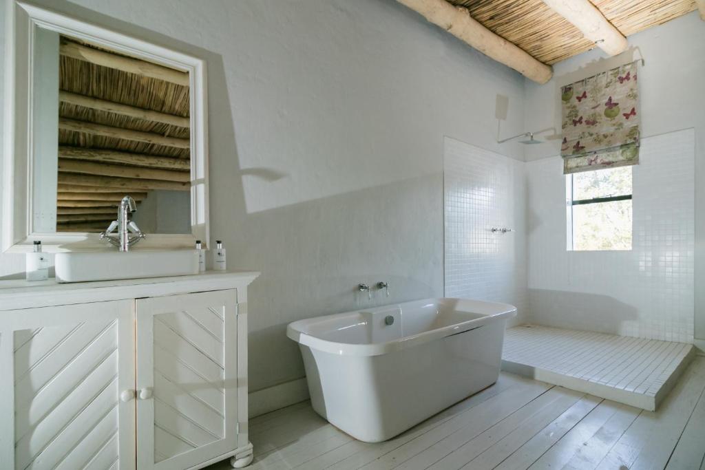 a white bathroom with a sink and a tub at The Whyte House in Graaff-Reinet